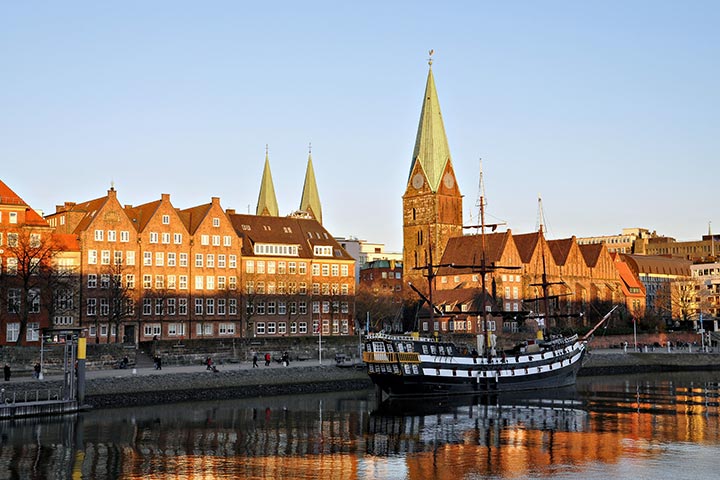 Historisches Schiff auf der Weser mit Blick auf die Altstadt von Bremen im Sonnenuntergang